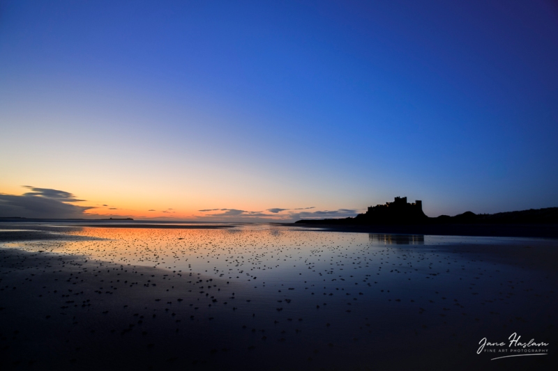 Early morning light with the silhouette of Bamburgh Castle in the Distance, Northumberland, UK