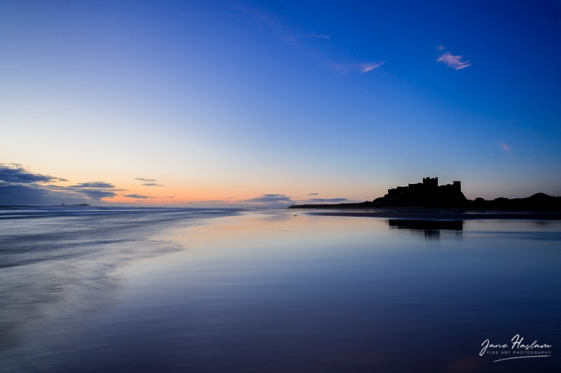 Low tide and silhouettes as dawn breaks at Bamburgh Castle
