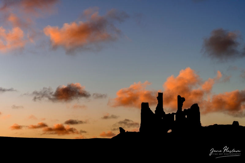 The ruins of Dunstanburgh Castle Silhouetted against a late evening sky 